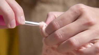 Örgü ören beyaz bir kızın genç kadın ellerine yakın çekim, nasıl düzgün örüleceğini gösteriyor. Yüzeyin derinliği. yüksek dinamik aralık.