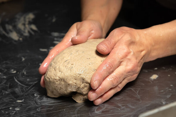 Close-up baker making bread, female hands, kneading dough, cooking