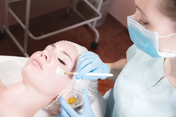 Πρόσωπο μιας νεαρής γυναίκας close-up ξαπλωμένη αισθητική διαδικασία εκτελείται εφαρμόζοντας μια αναζωογονητική μάσκα. — Φωτογραφία Αρχείου