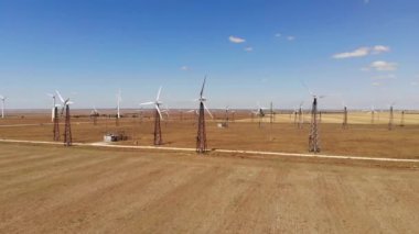 Geniş rüzgar türbinleri ve tarlada bıçaklar. Güneşli bir günde mavi gökyüzü parkı yavaş çekim drone dönüşü. alternatif enerji