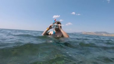 Kafkasyalı genç adam dalışa hazırlanıyor. Suda dururken şnorkelli maske takıyor ve hazırlanıyor..