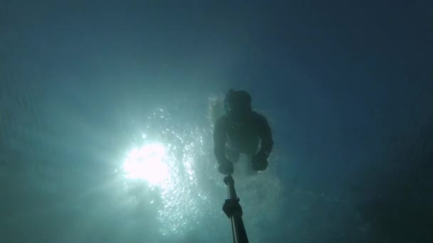 Mladý běloch plavající pod vodou v masce a šnorchlu s ploutvemi fotící se na selfie tyčce a akční kameře — Stock video