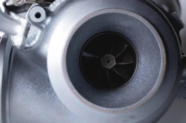 Nahaufnahme eines Autoteils für einen Verbrennungsmotor. Gas turbine. Turbo-Kompressor neu auf grauem Hintergrund. Teile Hintergrund — Stockfoto
