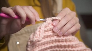 Örgü ören beyaz bir kızın genç kadın ellerine yakın çekim, nasıl düzgün örüleceğini gösteriyor. Yüzeyin derinliği. yüksek dinamik aralık.