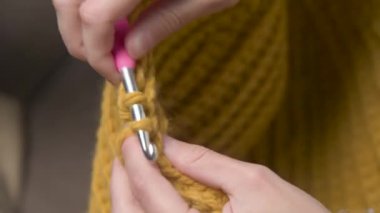Örgü ören beyaz bir kızın genç kadın ellerine yakın çekim, nasıl düzgün örüleceğini gösteriyor. Yüzeyin derinliği. yüksek dinamik aralık.