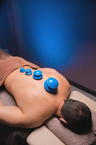 Vacuum rubber cups for cupping therapy on the back of a naked man. Massage at the spa, getting medical treatment for the back. Revitalizing and relaxing massage, fitness treatments