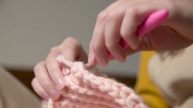 Örgü ören beyaz bir kızın genç kadın ellerine yakın çekim, nasıl düzgün örüleceğini gösteriyor. Yüzeyin derinliği. yüksek dinamik aralık.