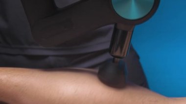 Yakın plan erkek masör masaj perküsyon aparatıyla erkek bir sporcunun bacağına masaj yapıyor. Şok dalgası terapisi