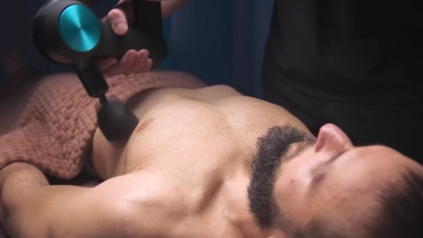 Close-up of percussion massage with a massage machine of the chest and chest area of a man to a client. Professional shock wave session in the massage therapists office — Video Stock
