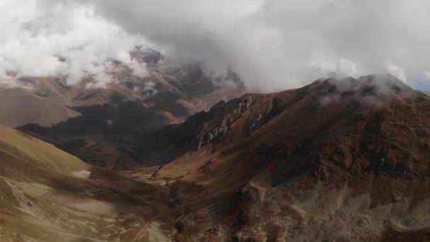 Aerial view flying through the clouds in the highlands against the backdrop of epic mountain peaks. Weather and climate change — Stock Video