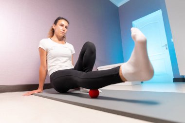 Atletik beyaz tenli kadın, masaj odasında kalçasına ve kalça kaslarına miyofasyal masaj yapıyor.