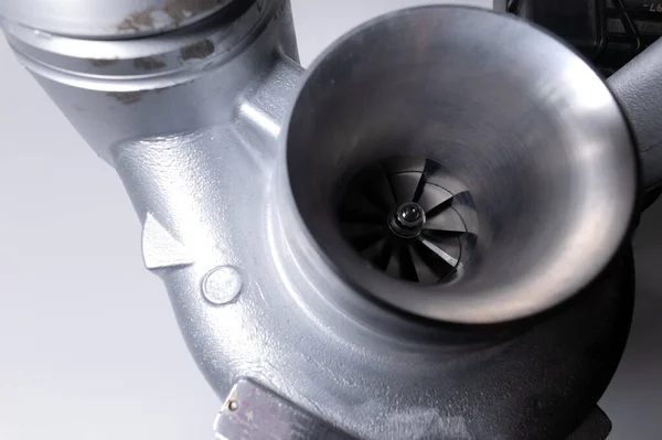 Close-up de uma peça automática para um motor de combustão interna. Turbina a gás. Super carregador Turbo novo em um fundo cinza. Parte de fundo — Fotografia de Stock