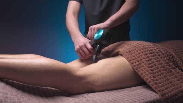 Erkek masör, masaj perküsyon aparatıyla erkek bir sporcunun bacağına masaj yapıyor. Şok dalgası terapisi — Stok video