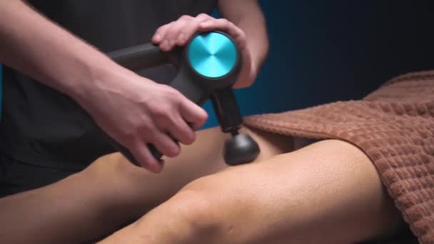 Homme masseur masculin masse la jambe d'un client athlète masculin avec un appareil de percussion de massage. Thérapie par ondes de choc — Video