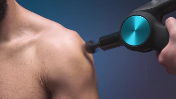Percussion massage of the shoulder of a male athlete with a shock wave massager — Stock Video