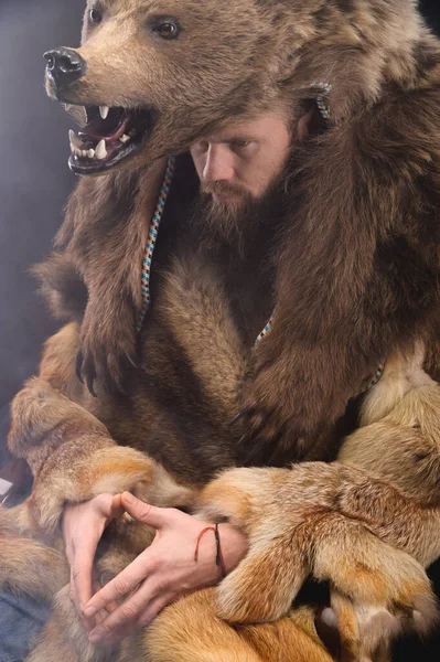 A bearded shaman is sitting dressed in skins, looking thoughtfully aside. Magic in business — Fotografia de Stock