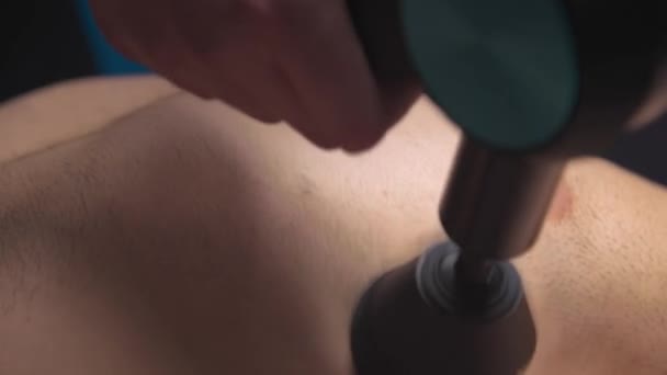 Close-up of percussion massage with a massage machine of the chest and chest area of a man to a client. Professional shock wave session in the massage therapists office — Wideo stockowe