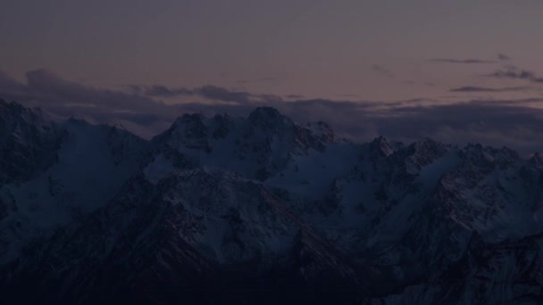 산높은 곳에서 눈덮인 가파른 산봉우리를 배경으로 구름 이 저녁 시간 여행을 하고 있다. 시간 여행 기상 변화 — 비디오