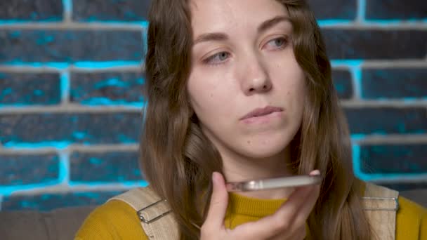 A friendly Caucasian girl uses a virtual assistant on her mobile phone. Smiling young white woman recording a reply to audio message on a social network. — 图库视频影像