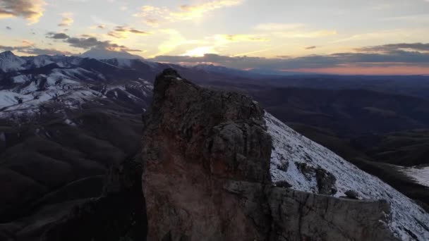 Extremely close at speed Aerial view of the top of a rocky mountain with mountain ranges and sunset sky. Evening time climbing the Caucasus mountains high-speed flight nearby — ストック動画