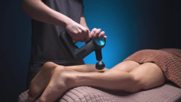 Professionelle Masseur Mann macht Massageübungen des Kronenmuskels für den Kunden mit einem Percussion-Vibro-Massagegerät. Schocktherapie zur regenerierenden Massage des athletischen Körpers. — Stockvideo