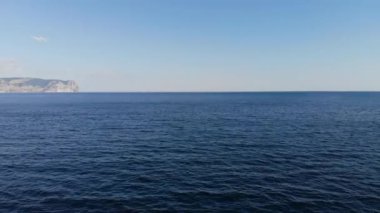 Arka planda kayalık bir kıyıya sahip okyanus yüzeyinde uçan bir uçak. Deniz arkaplanı