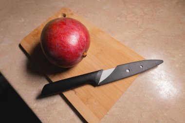 Olgun bir mango meyvesi kesme tahtasının üzerinde bir mutfak bıçağının yanında yatıyor. Sağlıklı bir atıştırmalık hazırlıyorum. Doğal besin antioksidanları