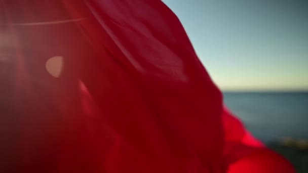 Primo piano di tessuto vestito rosso sulla donna attraente caucasica increspature nel vento. Passeggiata sul mare in tempo ventoso — Video Stock