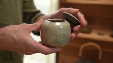 Çömlekçilerin yakın çekim güçlü elleri kendi elleriyle bitirilmiş teaware gösteriyor. Kravt çay seramiklerinin sunumu ve tanıtımı