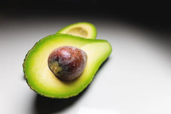 Färska grönsaker - Zutano avokado på ett vitt bord med svart bakgrund. Kontrasterande bild av en god grönsak — Stockfoto