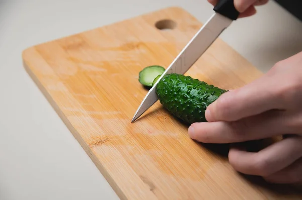 Primer plano de las manos femeninas cortando pepinos para una ensalada vegana. Cocina casera comida sana y saludable — Foto de Stock