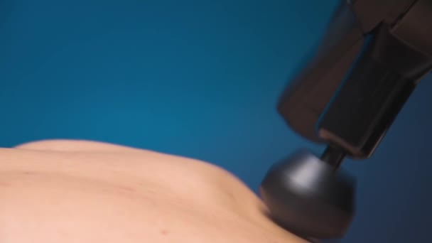 Maseur caucazian profesionist de sex masculin face un efect de vindecare asupra mușchilor spatelui superior al unui client de sex masculin folosind un masaj vibro percuție. Terapia de șoc pentru regenerarea corpului atletic de masaj. — Videoclip de stoc