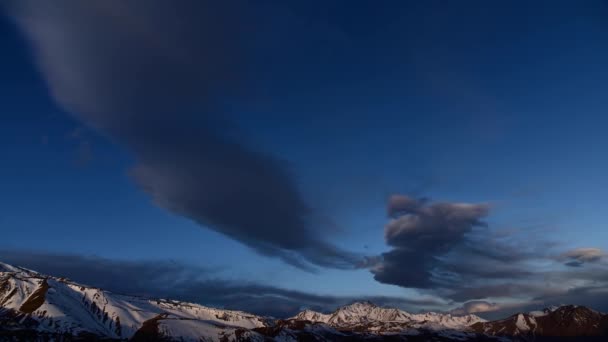 Movimiento vespertino del lapso de tiempo de nubes en lo alto de las montañas sobre el fondo de picos afilados nevados de las montañas. Cambio climático en el lapso de tiempo — Vídeo de stock