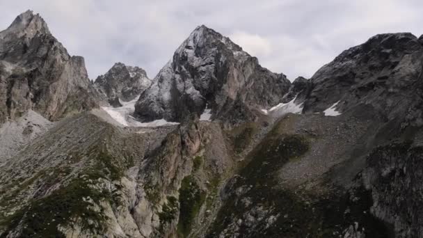 Vista aérea junto a las cimas de las montañas. Picos agudos de montañas rocosas con vegetación — Vídeo de stock