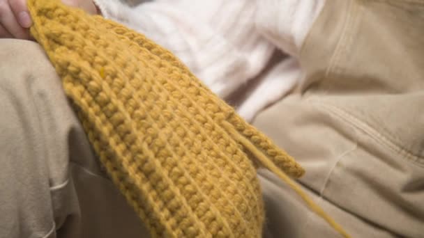 Close-up of the female hands of a Caucasian young woman unraveling a knitted product. Home knitting — Stock Video