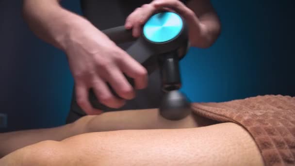 Mężczyzna masażysta robi ćwiczenia masażu na udach z pomocą perkusji vibro masażera do męskiego klienta. Terapia wstrząsowa dla regeneracyjnego masażu ciała sportowca. — Wideo stockowe