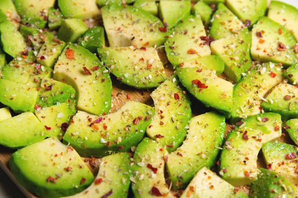 Large slices of sliced ripe avocado lie textured on a wooden cutting board. Sprinkled with spices. Healthy food. Vegetarianism — Stock Photo, Image