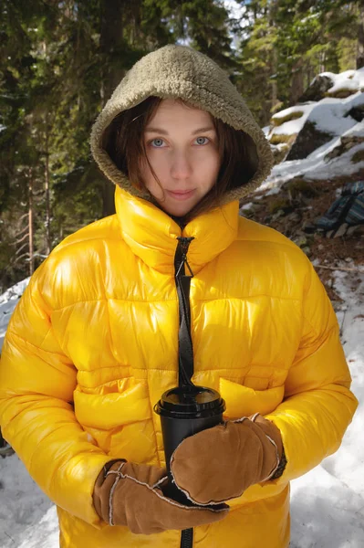 ジャケットに身を包んだ白人女性は紙コップや針葉樹林を持ち — ストック写真