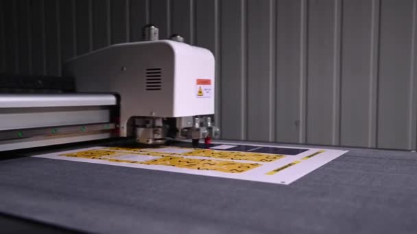 Primo piano profondità di campo poco profonda un plotter di produzione in una stamperia taglia automaticamente l'imballaggio e le etichette da cartone — Video Stock