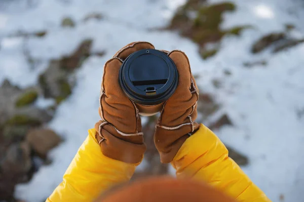 Papírový kelímek v rukou v palčácích, v přírodě na pozadí sněhu — Stock fotografie