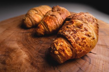 Tahta bir tepside taze pişmiş üç kruvasan. Lezzetli ve sağlıklı kahvaltı.