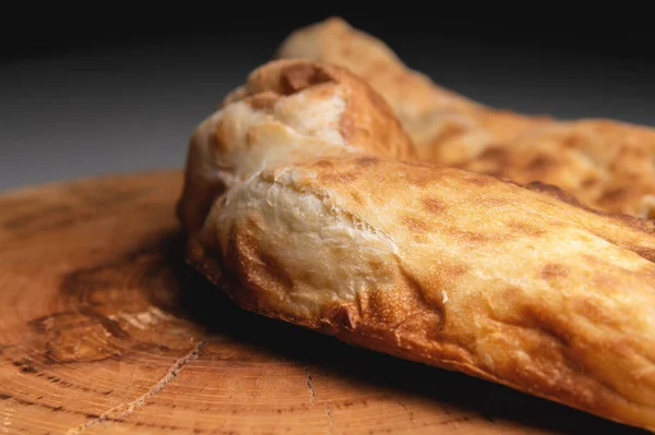 Close-up khachapuri frito cozido no forno encontra-se em uma tábua de madeira — Fotografia de Stock