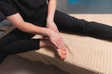 Miyofasyal kendine masaj. Beyaz erkek masör, içeride kas ve bacak bağları masajı yapıyor.