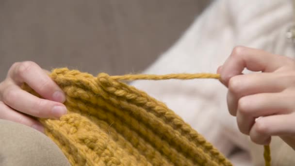 Gros plan des mains féminines d'une jeune femme caucasienne démêlant un produit tricoté. Tricot à domicile — Video