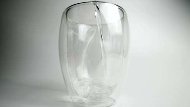 Stüdyo resmi beyaz arka planda şeffaf bir cam bardağa dökülüyor. İçme suyu — Stok video