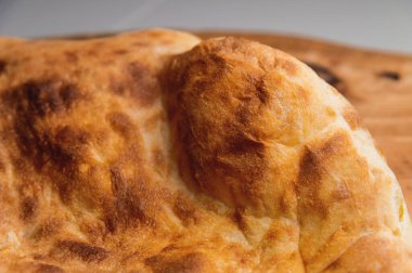 Fırında kızartılmış khachapuri ahşap bir tahtanın üzerinde yatıyor.