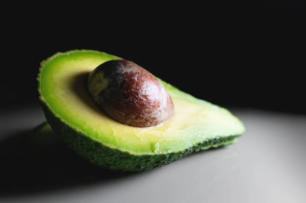 Beyaz bir masada yarım bir avokado. kontrastlı atış yumuşak odak — Stok fotoğraf