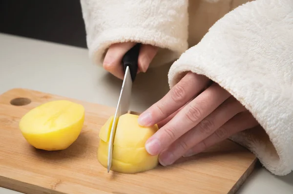Perempuan di kamar mandi memotong kentang mentah untuk memotong papan kayu di dapur rumah — Stok Foto