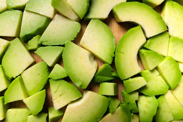 Närbild av färsk välsmakande finhackad skalad avokado på en träskärbräda. Vegetarianism perfekt bakgrund — Stockfoto