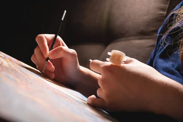 Primer plano de una artista femenina pintando a mano con acuarelas en lienzo con un pincel en un estudio de arte moderno oscuro. El concepto de artista joven o artista femenina. —  Fotos de Stock